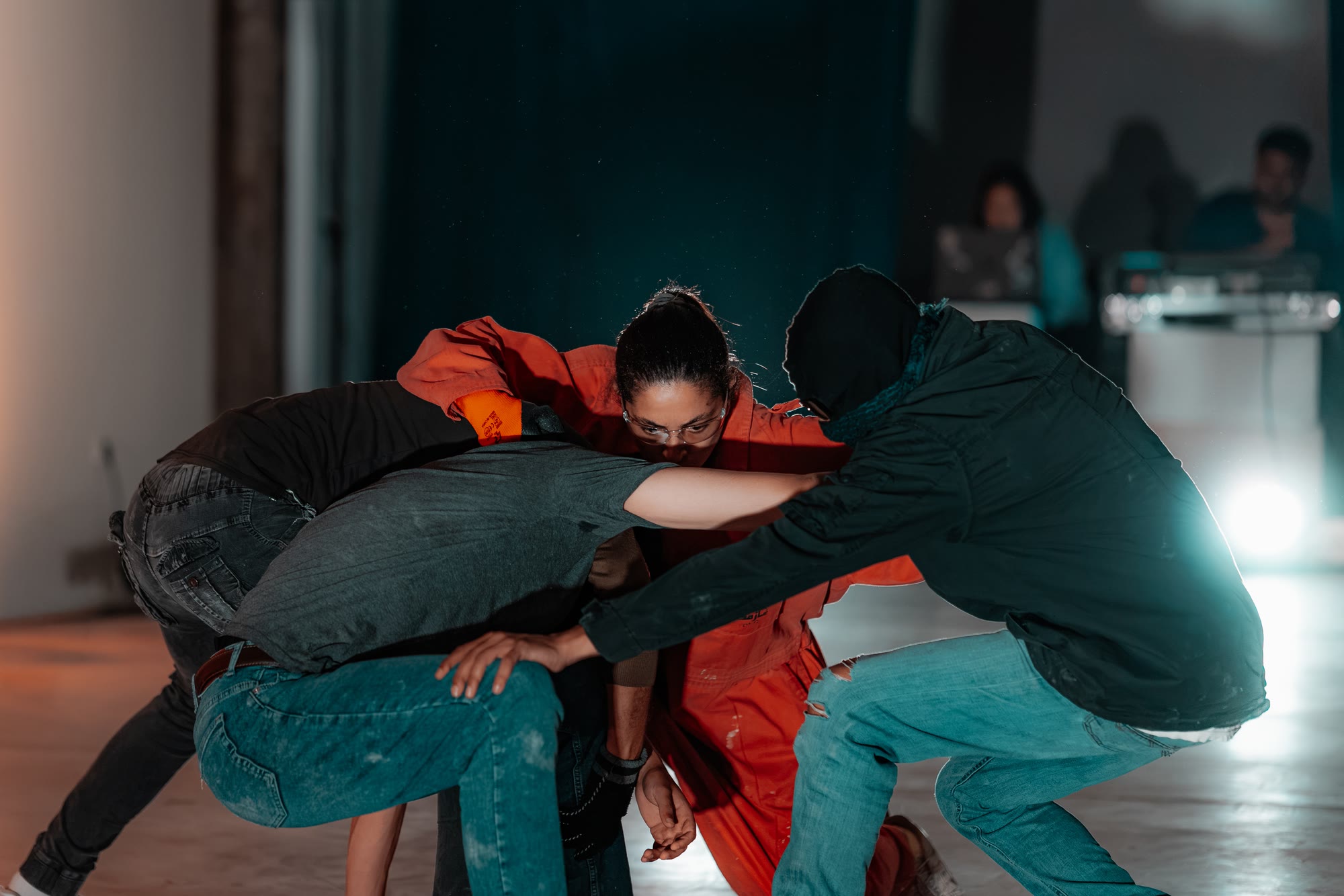 Four performers lock arms in a tight huddle